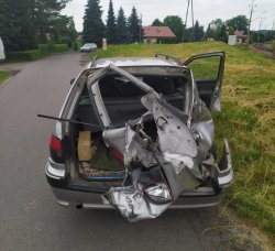 Zniszczony srebrny samochód osobowy typu kombi. Widok z tyłu.