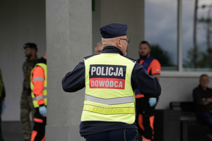 Policyjny Dowódca odpowiedzialny za działania, w tle ratownicy medyczni