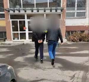 Policjant po cywilnemu prowadzi skutego kajdankami męzczynę