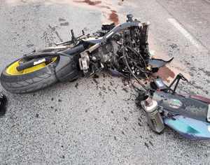 zniszczony motocykl leżący na drodze asfaltowej
