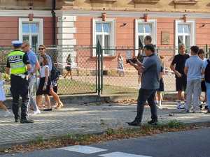 Policjant ruchu drogowego rozdający uczniom elementy odblaskowe