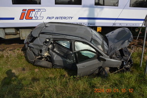 Zniszczony Jeep stojący obok torów kolejowych, za nim wagon pociagu Intercity