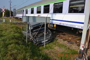 Zniszczony Jeep stojący obok torów kolejowych, za nim wagon pociągu Intercity