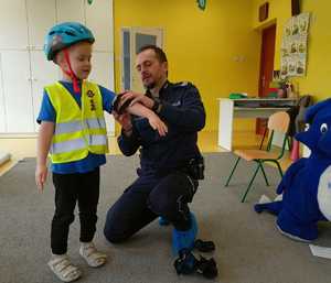 policjant pokazuje jak prawidłowo założyć ochraniacze na łokcie i kolana