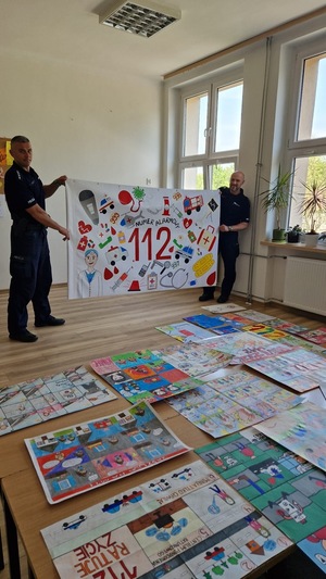 Dzielnicowy asp. sztab. Tomasz Tchoń oraz asp. sztab. Paweł Mróz trzymający plakat wykonany przez dzieci