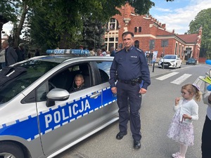 asp.sztab. Janusz Buratowski stojący obok radiowozu policyjnego
