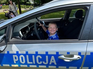 Chłopiec siedzący za kierownicą policyjnego radiowozu