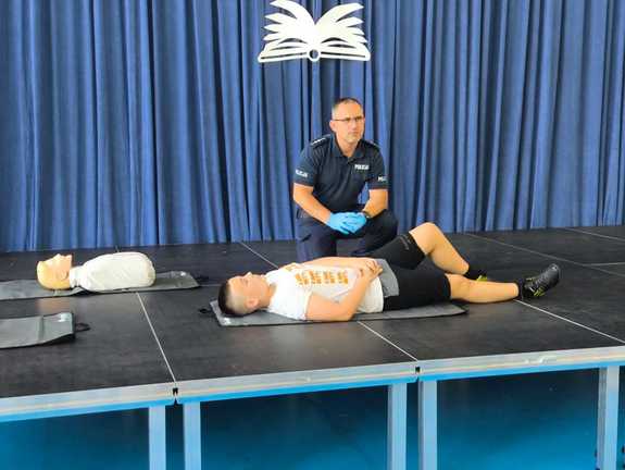 policjant wykonujący pokaz udzielania pierwszej pomocy