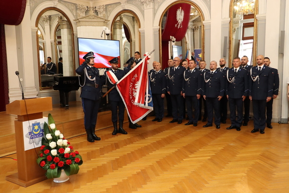 Funkcjonariusze ze sztandarem uroczyście odśpiewują hymn.