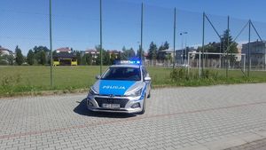 Radiowóz Policji na tle boiska i placu zabaw