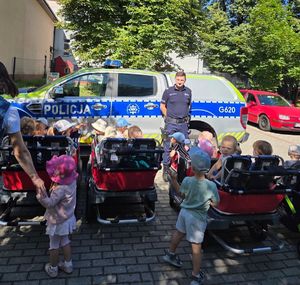 Dzielnicowy na tle radiowozu policyjnego