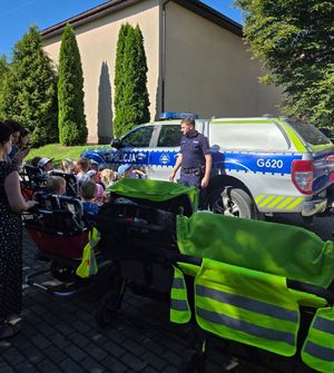 Dzielnicowy na tle radiowozu policyjnego