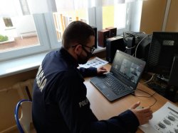 Umundurowany policjant przed laptopem podczas lekcji on-line