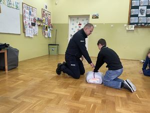 policjant KMP opisujący uczniowi jak prawidłowo prowadzić RKO