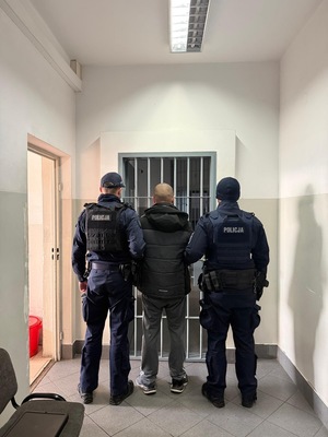 zatrzymany mężczyzna doprowadzany przez umundurowanych funkcjonariuszy do PDOZ