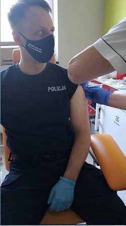 Umundurowany policjant przyjmujący szczepionkę