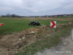 Czarny motocykl stojący oparty na podnóżce poza jezdnia i rowem melioracyjnym