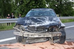 zniszczona pokrywa silnika ciemnego BMW, rozbite przednie lampy, oderwany zderzak