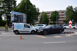 Czołowe zderzenie czarnego samochodu z białym samochodem dostawczym