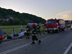 Miejsce wypadku, po prawej dwa wozy strażackie i strażacy, po lewej biały samochód w rowie melioracyjnym