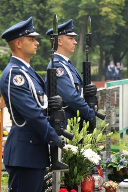 dwaj umundurowani policjanci trzymają wieniec