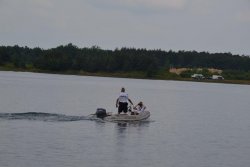 Dwóch funkcjonariuszy policji na pontonie motorowym, w tle drzewa