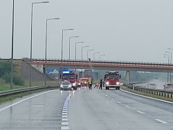 Samochody straży pożarnej zabezpieczające miejsce wypadku na autostradzie. Pogoda pochmurna i silnie padający deszcz.