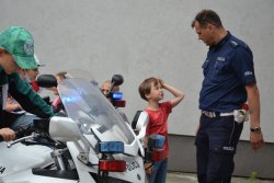 po prawej stronie policjant z dzieckiem, po lewej dziecko siedzące na motorze policyjnym