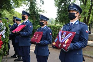 policjanci w trakcie trwania uroczystości pogrzebowych trzymają odznaczenia państwowe