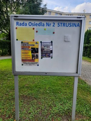 tablica informacyjna Rady Osiedla Strusina w Tarnowie z powieszonym plakatem i ulotką profilaktyczną