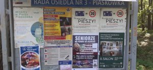 tablica informacyjna Rady Osiedla Piaskówka w Tarnowie z powieszonym plakatem i ulotką profilaktyczną