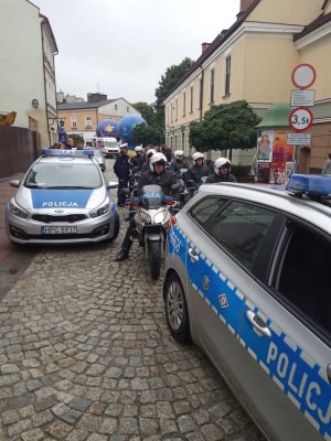 Policjanci na motorach oraz dwa radiowozy policyjne