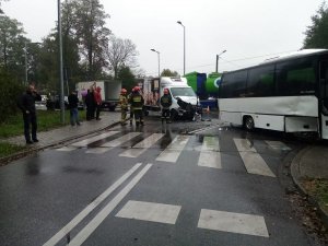 Ogólne miejsce wypadku, widoczne uszkodzenia autobusu i samochodu dostawczego, na drodze stoją strażacy i świadkowie zdarzenia