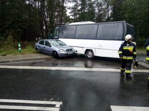 Samochód osobowy i autobus, obok stoi strażak