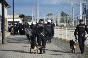 Policjanci eskortujący grupkę kibiców na stadion sportowy