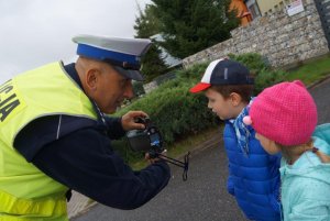 Policjant ruchu drogowego instruuje dziecko o możliwościach rejestracji fotoradaru