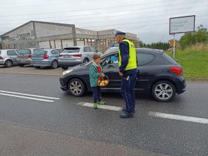 Policjant oraz dziecko podczas kontroli jednego samochodu osobowego