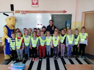 Dzieci wraz z mega pluszową mrówką przed edukacyjną planszą pasów (zebry)