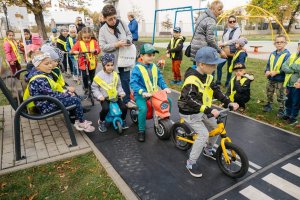 dzieci w kamizelkach odblaskowych jadące na rowerkach