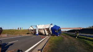 Samochód ciężarowy podczas stawiania na koła, obok stoją mężczyźni z elementami odblaskowymi na ubraniach