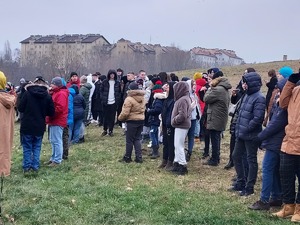 Grupa ludzi stojaca na trawniku coś obserwujaca