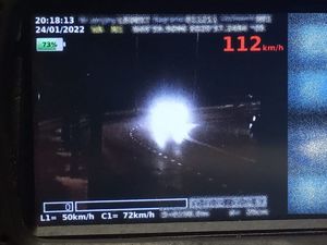 Zdjęcie zrobione nocą zbliżającego się samochodu. Po prawej stronie u góry prędkość 112 km/h, po lewej data 24.01.2022 r. i godzina 20.18