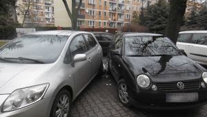 Dwa samochody osobowe stojące obok siebie, po lewej jasny, po prawej ciemny volkswagen, między nimi porozrzucane plastikowe elementy