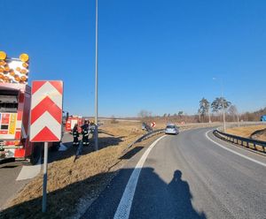 Ogólne miejsce wypadku, po lewej wóz strażacki oraz strażacy, po prawej stronie radiowóz, w oddali widać uszkodzony samochód osobowy stojący na pasie zielni