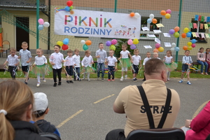 grupka dzieci stojących w rzędzie, z tyłu widoczny napis PIKNIK RODZINNY