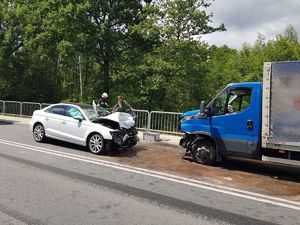 Zdjęcie przedstawia dwa samochodu stojące przodem do siebie na jednym pasie ruchu z uszkodzeniami przodów