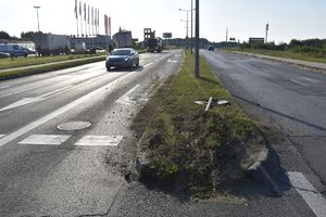 Przewrócony znak drogowy. W tle przyczepa ciężarowa i samochód straży pożarnej