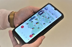 Telefon komórkowy w rękach osoby z wyświetlona Krajową Mapą Zagrożeń Bezpieczeństwa