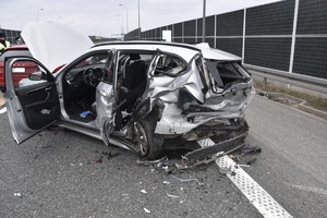 uszkodzony srebrny samochód BMW, dookoła porozrzucane plastikowe elementy i szkło