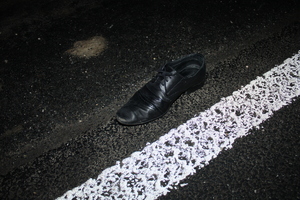 czarny, elegancki but leżący na drodze